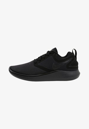 Chaussure de sport noire avec une tige en textile lisse, des accents texturés et une semelle rembourrée. Caractérisée par un bout rond et une fermeture à lacets.