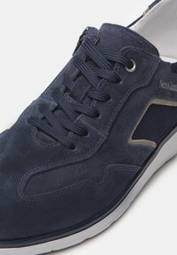 Sneaker in suede blu navy con chiusura a lacci, pannello laterale in mesh e dettagli contrastanti grigi. Suola in gomma con bordi bianchi.
