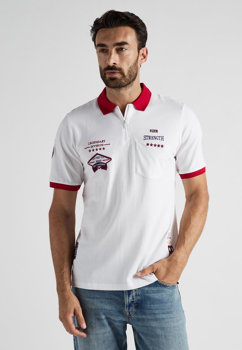 Biała koszulka polo z czerwonym kołnierzykiem i mankietami, z zamkiem błyskawicznym na szyi, kieszenią z przodu oraz wyszywanymi detalami na piersi i rękawie.
