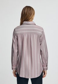 Camicia a maniche lunghe a righe rosa chiaro con colletto classico, polsini con bottone e pieghe posteriori per un comfort aggiuntivo e una vestibilità rilassata.