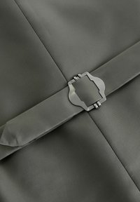 Tkanina w kolorze oliwkowym o teksturze z eleganckim srebrnym zapięciem przy zamknięciu klapy. Projekt cechuje się czystymi liniami i minimalistyczną estetyką.
