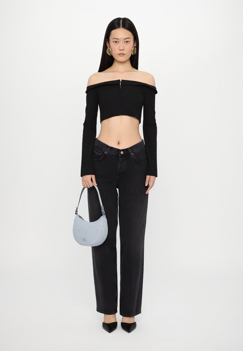 Crop top noir dénudé sur les épaules avec des manches longues, jean noir taille haute, et un sac à main bleu clair, associés avec des escarpins noirs à bout pointu.