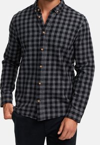 Czarno-szara koszula w kratę z flaneli na guziki; długie rękawy, zaokrąglony kołnierz i drewniane guziki; teksturowana tkanina.