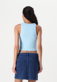 Lys blå ribbet kort topp med rund hals, kombinert med en mørk denim miniskjørt med baklommer og en tettsittende liv.