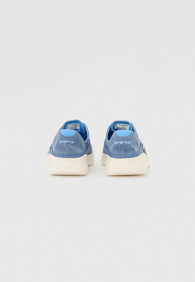 Niebieskie płótnowe buty z białymi podeszwami, z teksturowanym tyłem i subtelnym logowaniem. Projekt ma niski cholewkę z zaokrąglonymi krawędziami.