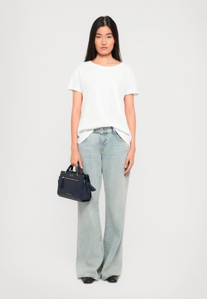 White short-sleeve T-shirt with a subtle pattern, light blue wide-leg jeans, and a small navy handbag with gold hardware and accents.