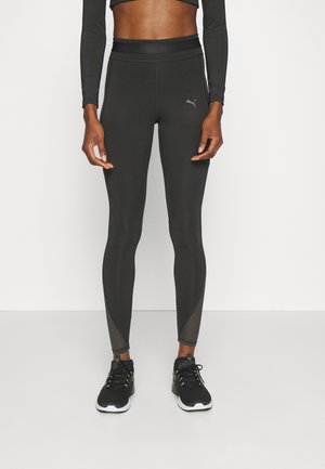 Leggings de sport noirs avec une taille haute, texture lisse et accents en maille au niveau des jambes inférieures. Logo affiché sur la cuisse.
