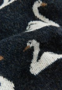 Tkanina dziana z ciemnoniebieskim tłem w białe i beżowe wzory łabędzi. Miękki, teksturowany materiał wełniany z drobnymi detalami.