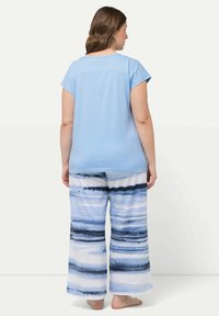 Blå bomullstopp med kort ärm i kombination med vida byxor med horisontella blå och vita ränder. Mjuk textur, avslappnad passform.