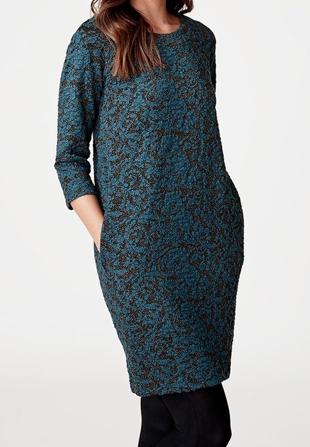 Robe à motifs bleus et noirs avec des manches longues, un col rond et des poches latérales. Le tissu a une finition texturée.
