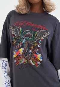 Grafische zwarte t-shirt met een meerkleurig drakenontwerp met strass, gecombineerd met tijgerafbeeldingen en gedurfde tekstaccenten.