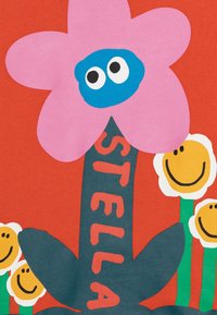 Barevná květinová grafika na červeném pozadí zobrazuje velký růžový květ s modrým středem, zeleným stonkem a usmívajícími se bílými sedmikráskami pod ním.