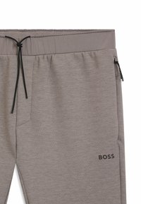 Graue Jogginghose mit Zugbandbund, Seitentasche und feiner Textur. Mit einem schwarzen "BOSS"-Logo an der Seite.