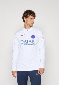 Bijela majica dugih rukava za trening s visokim ovratnikom, sadrži crveni Nike logo i plavi grafički prikaz "Qatar Airways" sprijeda.