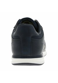 Baskets de sport bleu marine avec une tige en cuir lisse et en mesh, un col rembourré et une semelle extérieure blanche. Présente des coutures sans jonction et un design minimaliste.