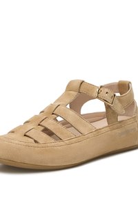 Sandal en suède beige avec un design ouvert, des sangles croisées, une boucle ajustable et une semelle intérieure rembourrée pour le confort. Surface lisse et texturée.