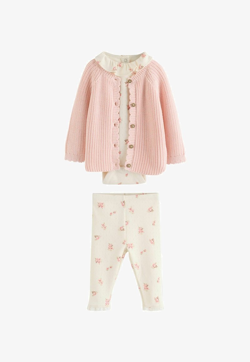 Cárdigan rosa de punto para bebé sobre un body crema con volantes y estampado floral con leggings a juego.