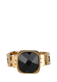 Zelta metāla gredzens ar lielu, facētu melnu akmeni kvadrātveida ietvarā. Josla ir ar izgriezumiem modernam dizainam.