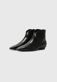 Bottes de cheville en cuir noir avec un design à bout pointu et un talon bas. Texture lisse avec une silhouette élégante et sans quincaillerie visible.