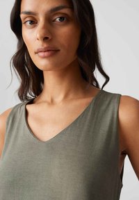 Khaki sleeveless top with a V-neck design. Soft, smooth texture and minimal seams, showcasing a relaxed fit.