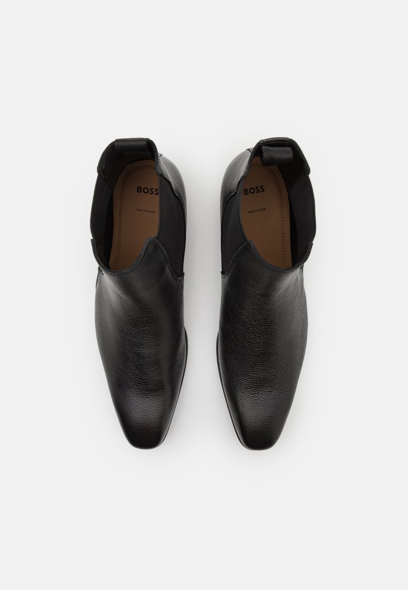 Chaussures en cuir noir au design épuré, à bout pointu, avec des panneaux latéraux élastiques et une texture lisse. Logo "BOSS" visible à l'intérieur.