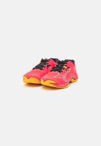 Scarpe da ginnastica rosse e nere con una tomaia liscia, dettagli gialli, suole texturizzate e lacci neri con un logo sul lato.