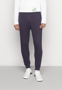 Lila sweatpants med en tapered passform, mjukt bomullsmaterial, ribbade muddar och en liten logotypsaccent på vänstra låret.