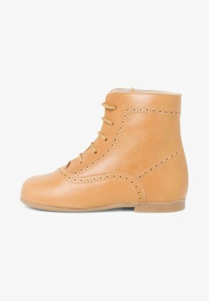 Botín de piel marrón con cierre de cordones, perforaciones decorativas, puntera redonda y una textura suave con un tacón bajo.