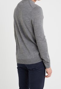 Grå tröja av mjukt stickat material, med långa ärmar och rund halsringning, med en slät yta och en figurnära design.