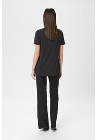 Svart kortärmad t-shirt med rundad nederkant, bärs tillsammans med svarta skräddarsydda byxor och eleganta svarta klackar. Slät, lättviktig tyg.