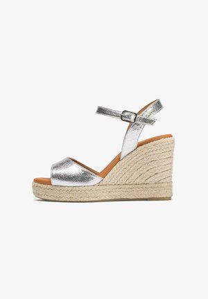 Sandales wedge métalliques argentées avec une semelle en corde d'espadrille, bout ouvert et bride à la cheville avec une boucle.