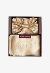Juego de sueños de pura seda en color dorado que incluye una funda de almohada de seda en forma de lazo y una máscara de sueño de seda a juego, todo presentado en una caja marrón.