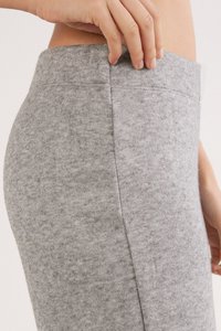 Leggings de tela elástica gris que muestran la cintura con una banda elástica plana, textura suave y diseño ajustado que realza la forma del cuerpo.