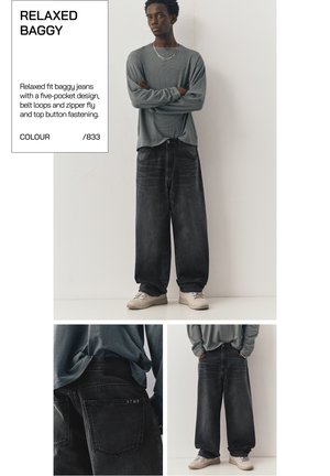 Junger Mann trägt locker sitzende schwarze Baggy-Jeans mit fünf Taschen und ein graues Langarmshirt, steht vor einer schlichten weißen Wand.