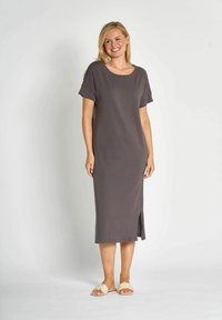 Graues knielanges Kleid mit kurzen Ärmeln, rundem Halsausschnitt und seitlichem Schlitz. Hergestellt aus weichem Stoff mit glatter Textur. Getragen mit hellen Sandalen.