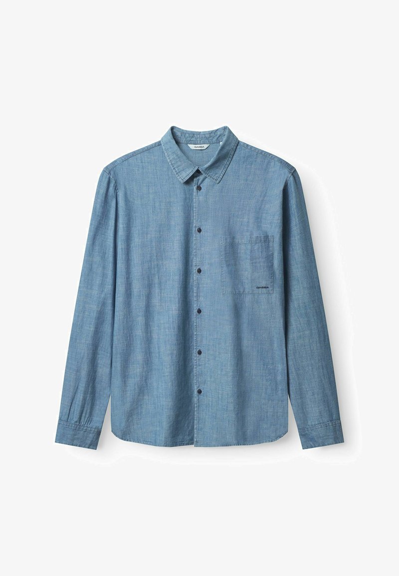 Lichtblauwe langharige blouse van chambray stof, met een borstzak en contrasterende donkere knopen.