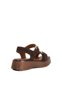 Brown suede platform sandals with two adjustable straps, gold hardware accents, and a wooden-textured sole.