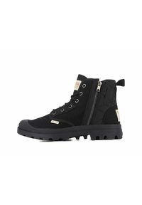 Botines negros de ante y goma. Cuentan con un cierre lateral, suela robusta con diseño de tacos y acentos metálicos con el logotipo.