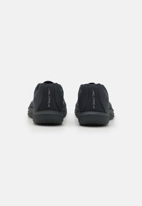 Chaussures de sport noires avec une tige en maille respirante, semelle rembourrée et accents subtils. Présentent un design à profil bas et un talon renforcé.