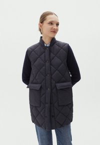 Gestepptes, ärmelloses Weste in Dunkelblau mit hohem Kragen. Verfügt über zwei Fronttaschen und runde Knöpfe, hergestellt aus strukturiertem Stoff.