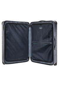 Valise à coque rigide grise avec un extérieur texturé, comportant deux compartiments, une poche zippée et une poignée robuste. L'intérieur est doublé de tissu foncé.