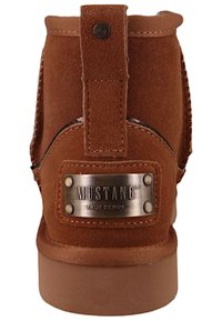 Brązowe zamszowe botki za kostkę z jasnobrązową gumową podeszwą, z metalową metką "MUSTANG TRUE DENIM" oraz dekoracyjnym przeszyciem z tyłu.