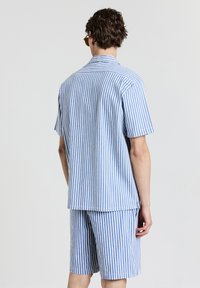 Leichtes Set aus kurzärmeligen, gestreiften Hemd und Shorts in Blau und Weiß. Verfügt über vertikale Streifen und ein klassisches Kragen-Design.