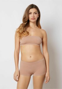 Nude bandeau-topp och matchande korta bottoms i mjukt, stretchigt tyg. Designen har en enkel, sömlös struktur.