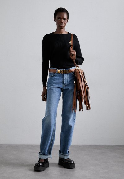 Μαύρο ριμπ πουλόβερ, ανοιχτό μπλε ψηλόμεσες τζιν, καφέ δερμάτινη τσάντα με φουντάκια, μαύρα παπούτσια με πλατφόρμα, χρυσή ζώνη με λεπτομέρειες λογότυπου.