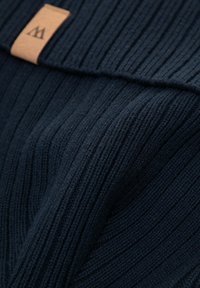 Tessuto di maglia a coste blu navy, con una superficie strutturata a sottili linee verticali e un piccolo'etichetta in pelle beige con un logo.