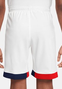 Witte sportieve shorts met een elastische tailleband en kleurgebroken marineblauwe en rode accenten aan de zoom. Textuurstof voor ademend vermogen.