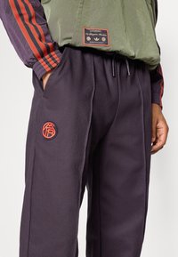 Μωβ υφασμένα παντελόνια με ελαστική μέση, που διαθέτουν πλαϊνές τσέπες και κόκκινο κεντημένο λογότυπο στο αριστερό μπούτι. Ελαφρύ υλικό.