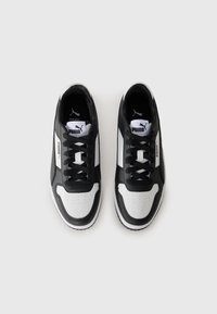 Black and white lace-up sneakers featuring synthetic leather material, rounded toe, contrasting panels, and prominent branding on the tongue.