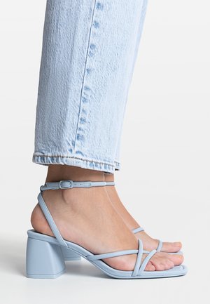 Sandalias celestes con tiras y tacón de bloque, con textura de cuero suave, tira ajustable en el tobillo y diseño de punta abierta.